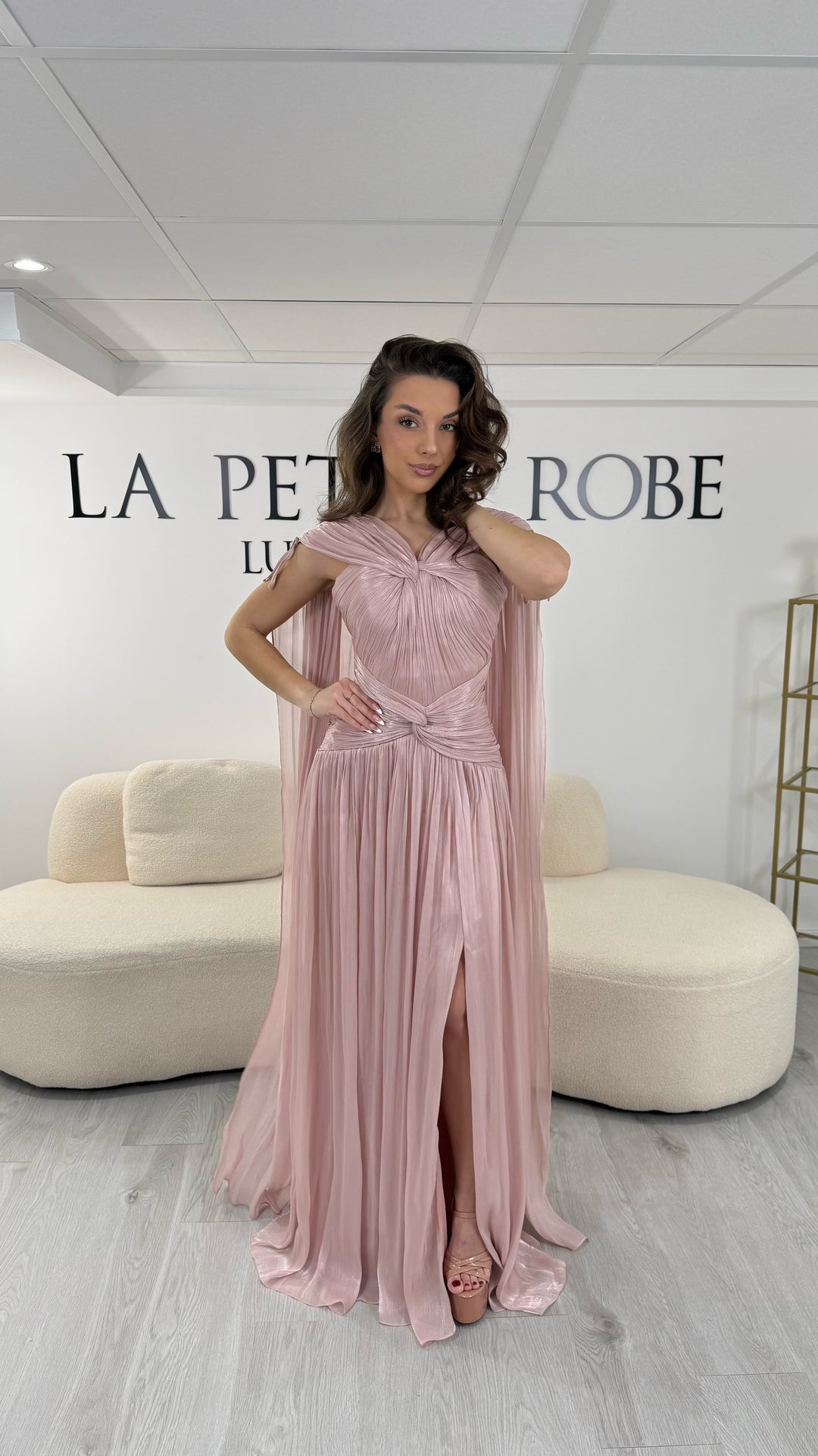 Robe de soirée rose élégante longue, col en V drapé, sans manche et dotée d’une fente raffinée. Coupe fluide et féminine idéale pour mariages et cérémonies.