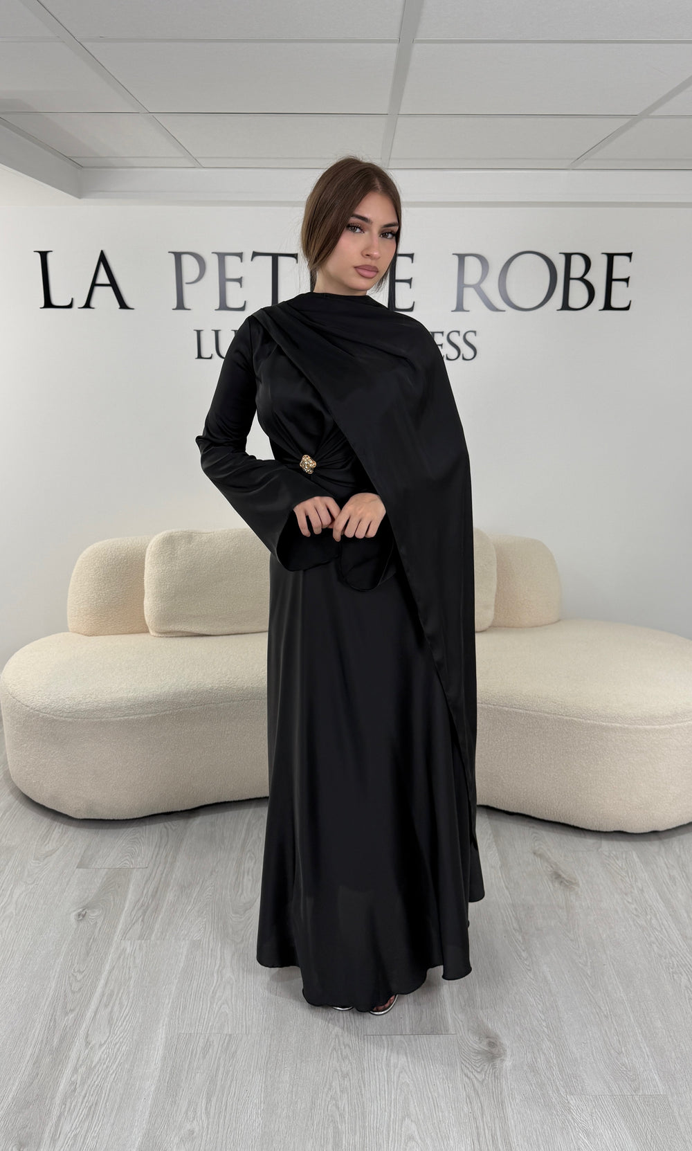 Robe de soirée modeste noire longue avec col rond, manches longues et drapé élégant. Une robe sans fente idéale pour mariage, cérémonie ou demoiselle d'honneur.