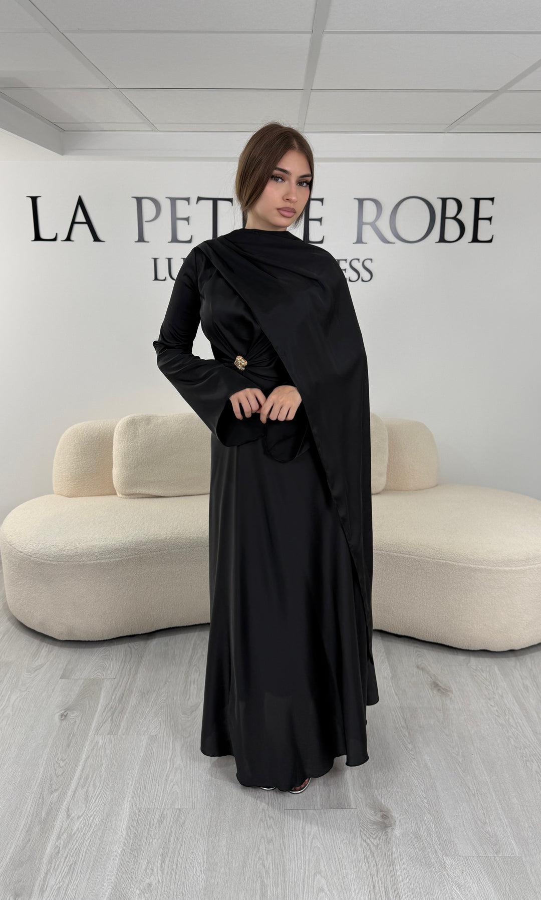 Robe de soirée modeste noire longue avec col rond, manches longues et drapé élégant. Une robe sans fente idéale pour mariage, cérémonie ou demoiselle d'honneur.