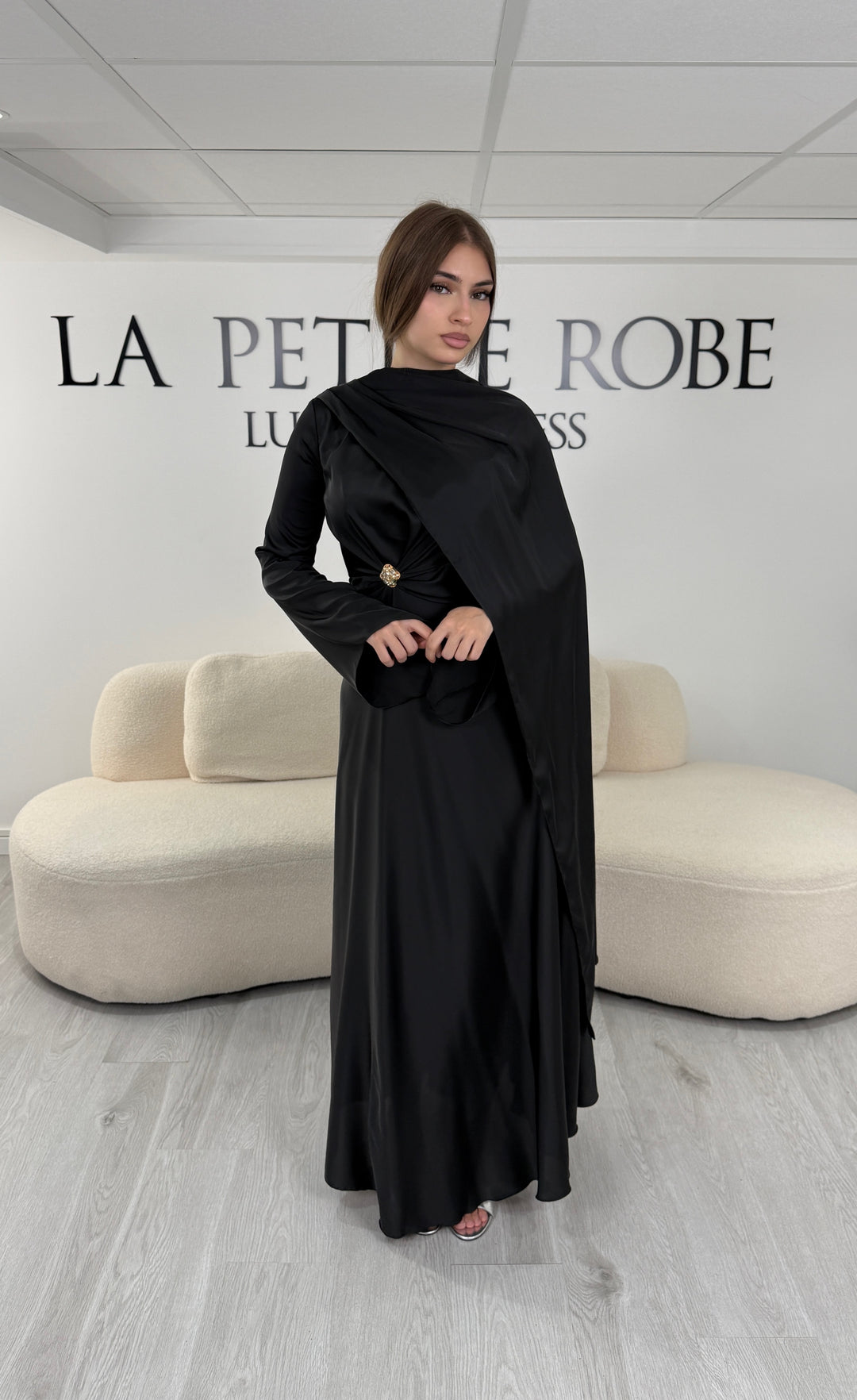Robe de soirée modeste noire longue avec col rond, manches longues et drapé élégant. Une robe sans fente idéale pour mariage, cérémonie ou demoiselle d'honneur.