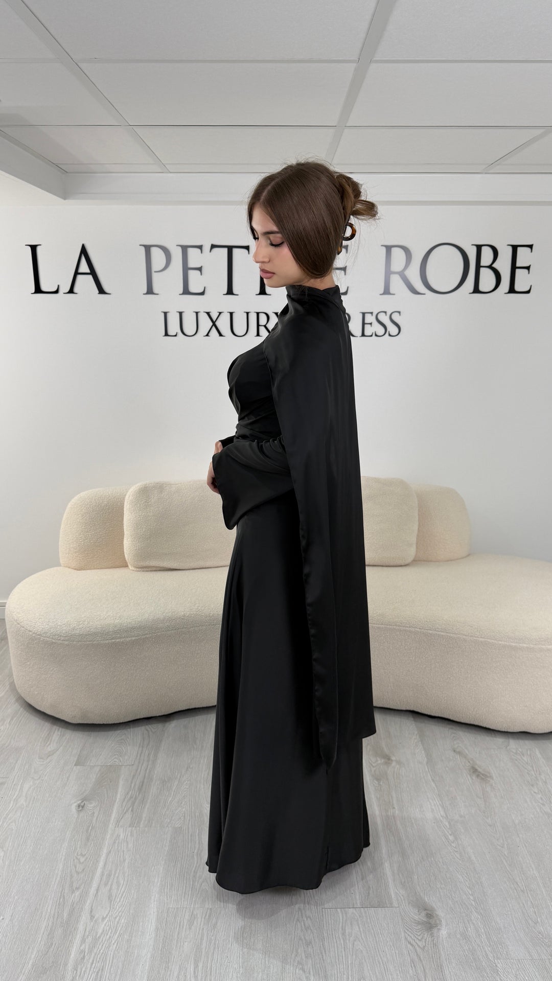 Robe de soirée modeste noire longue avec col rond, manches longues et drapé élégant. Une robe sans fente idéale pour mariage, cérémonie ou demoiselle d'honneur.