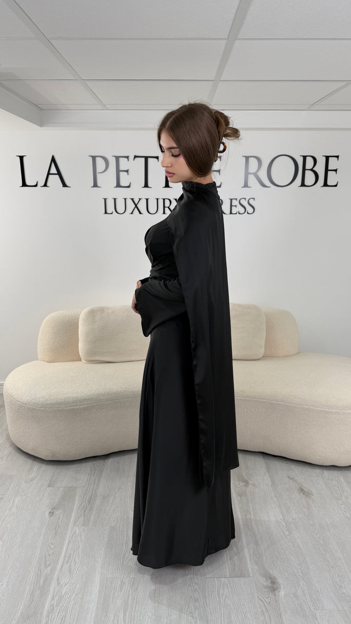 Robe de soirée modeste noire longue avec col rond, manches longues et drapé élégant. Une robe sans fente idéale pour mariage, cérémonie ou demoiselle d'honneur.