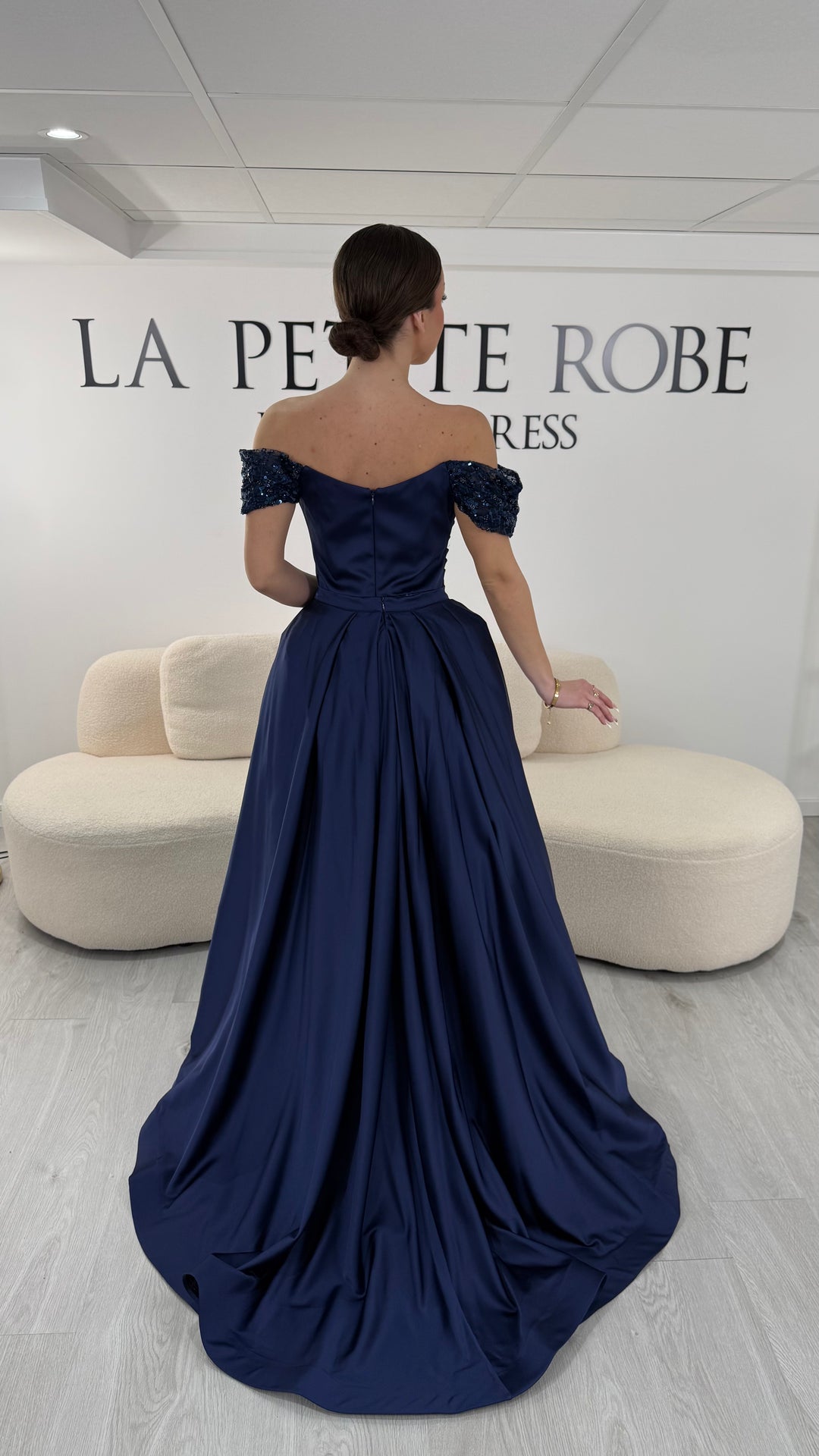 Robe de soirée bleu marine élégante sans manches avec col bardot et sequins. Robe longue sans fente idéale pour soirée chic.