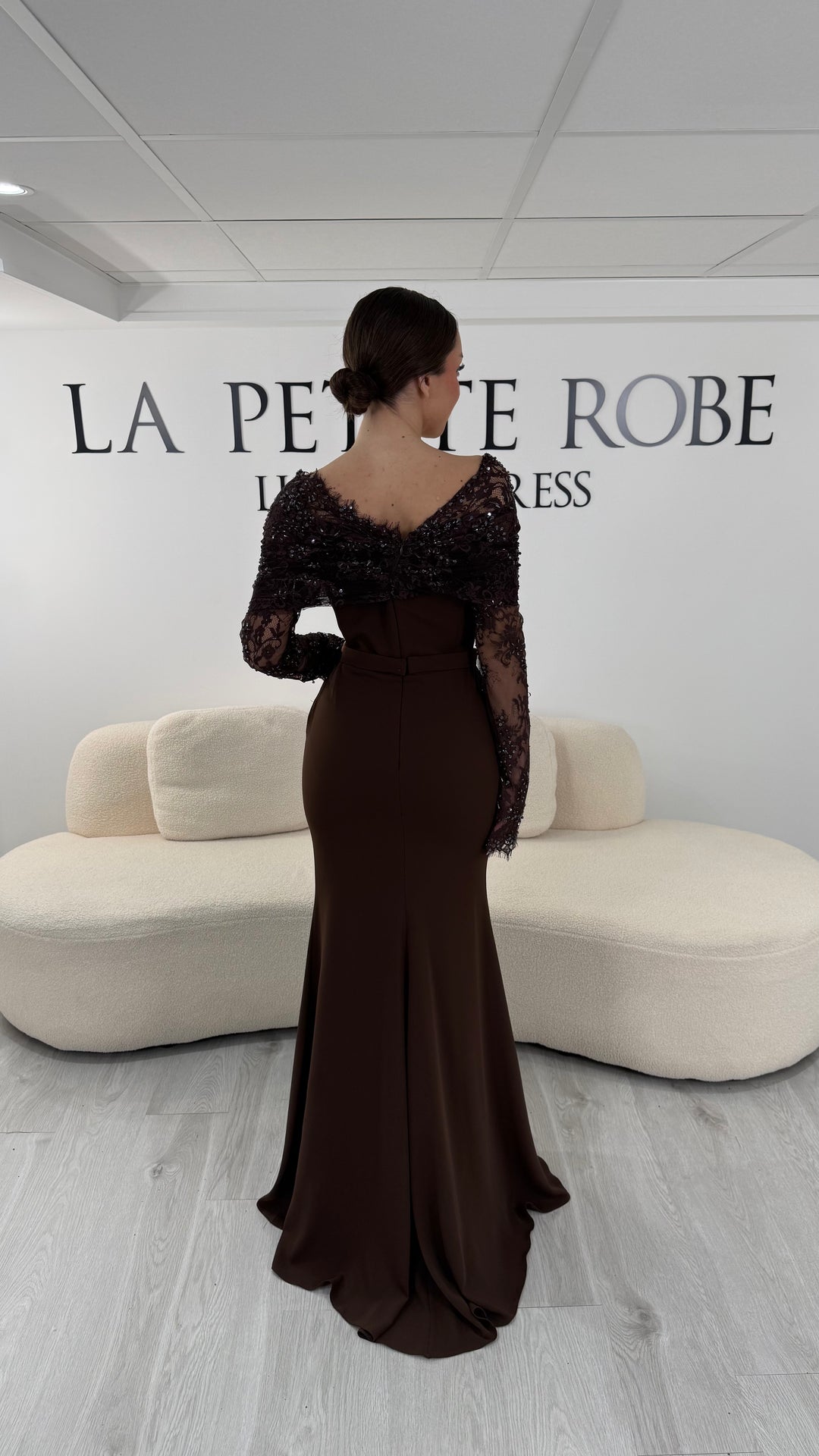 Robe de soirée marron élégante avec col bateau en dentelle et manches longues. Robe longue sans fente idéale pour soirée chic.