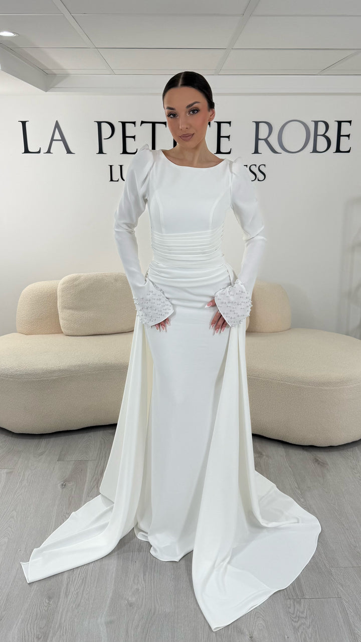 Robe de mariée blanche élégante avec col rond et manches longues. Robe longue sans fente, coupe raffinée et détails perlés, parfaite pour une cérémonie de mariage chic.