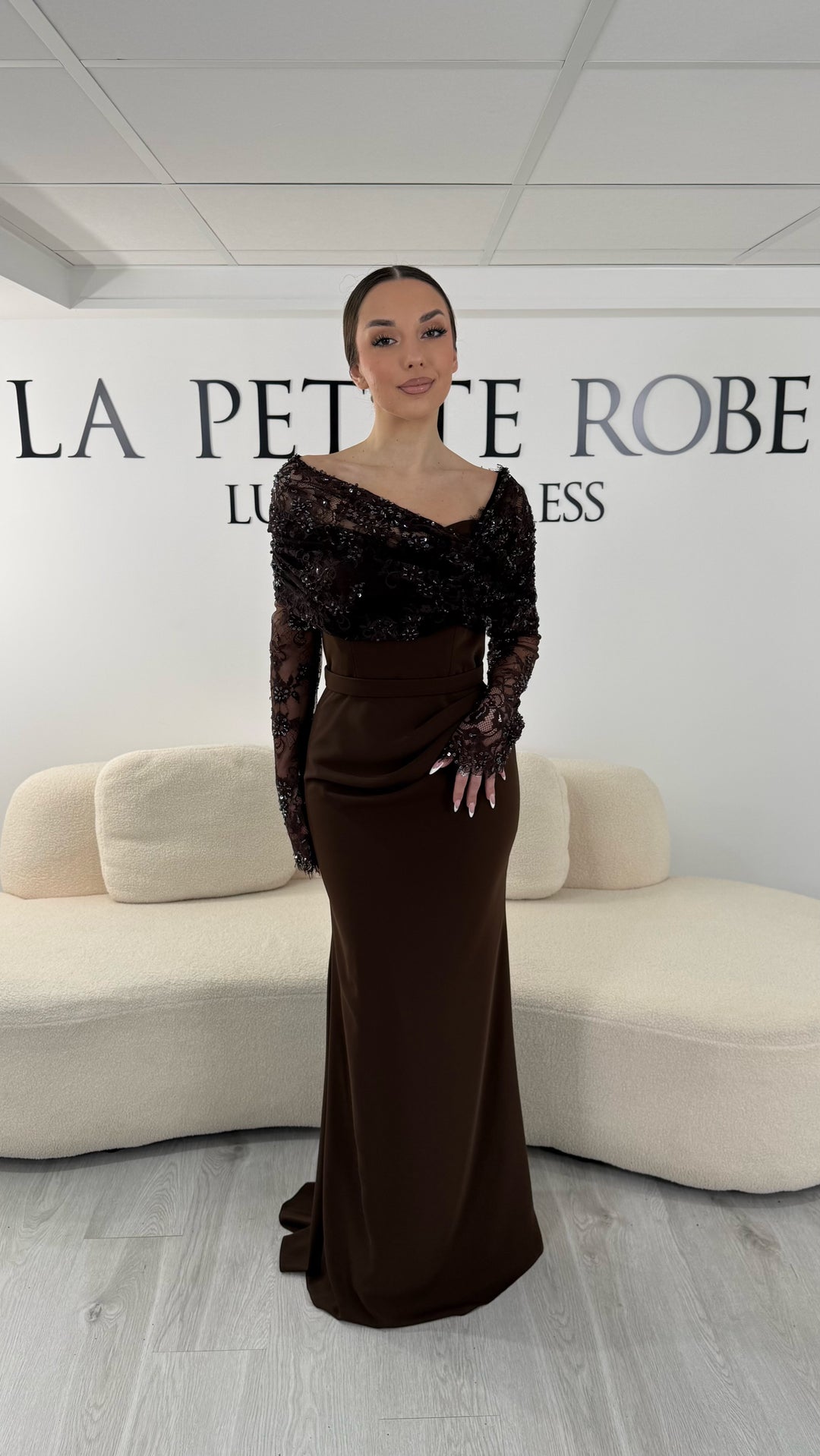 Robe de soirée marron élégante avec col bateau en dentelle et manches longues. Robe longue sans fente idéale pour soirée chic.