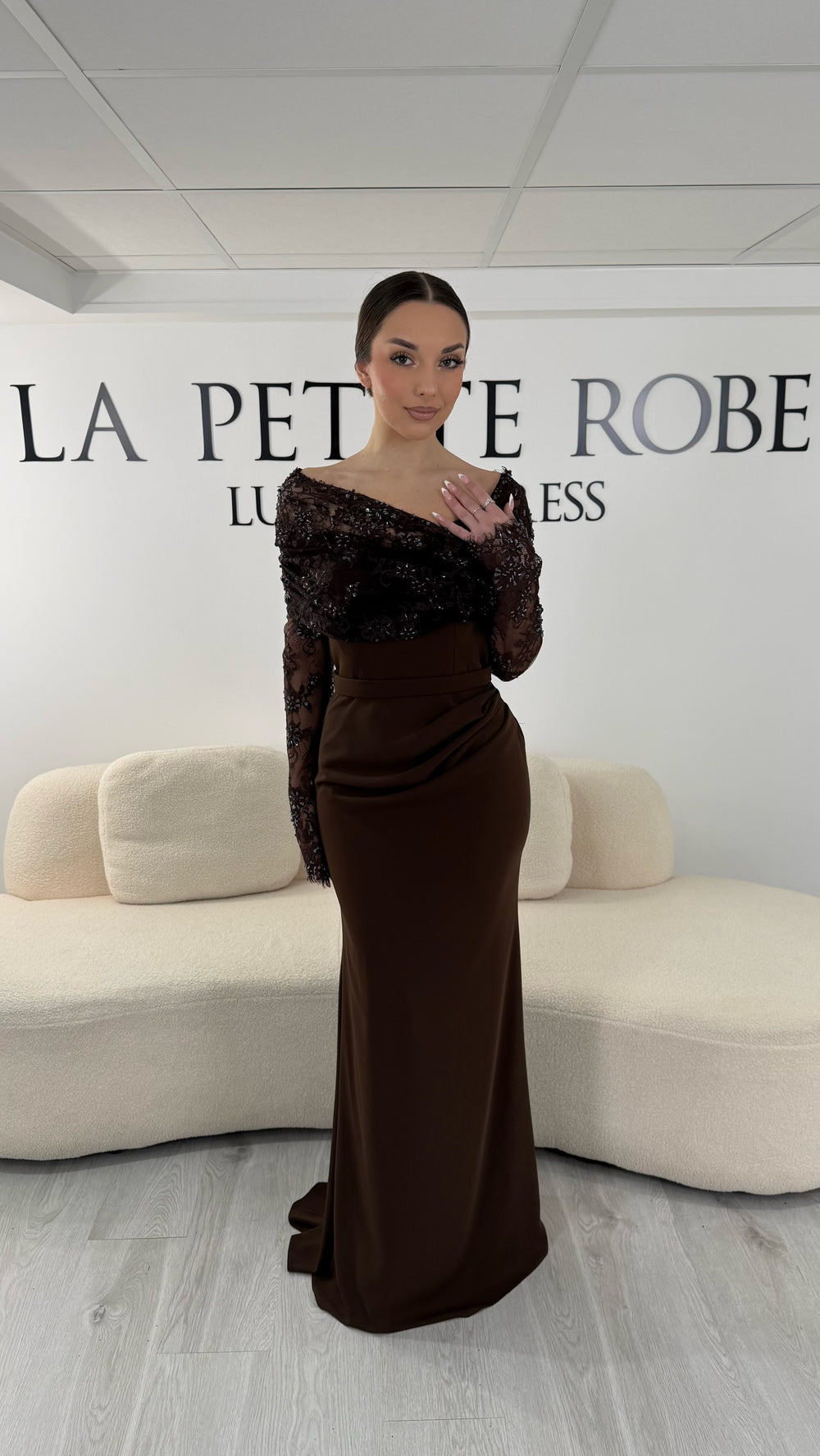 Robe de soirée marron élégante avec col bateau en dentelle et manches longues. Robe longue sans fente idéale pour soirée chic.