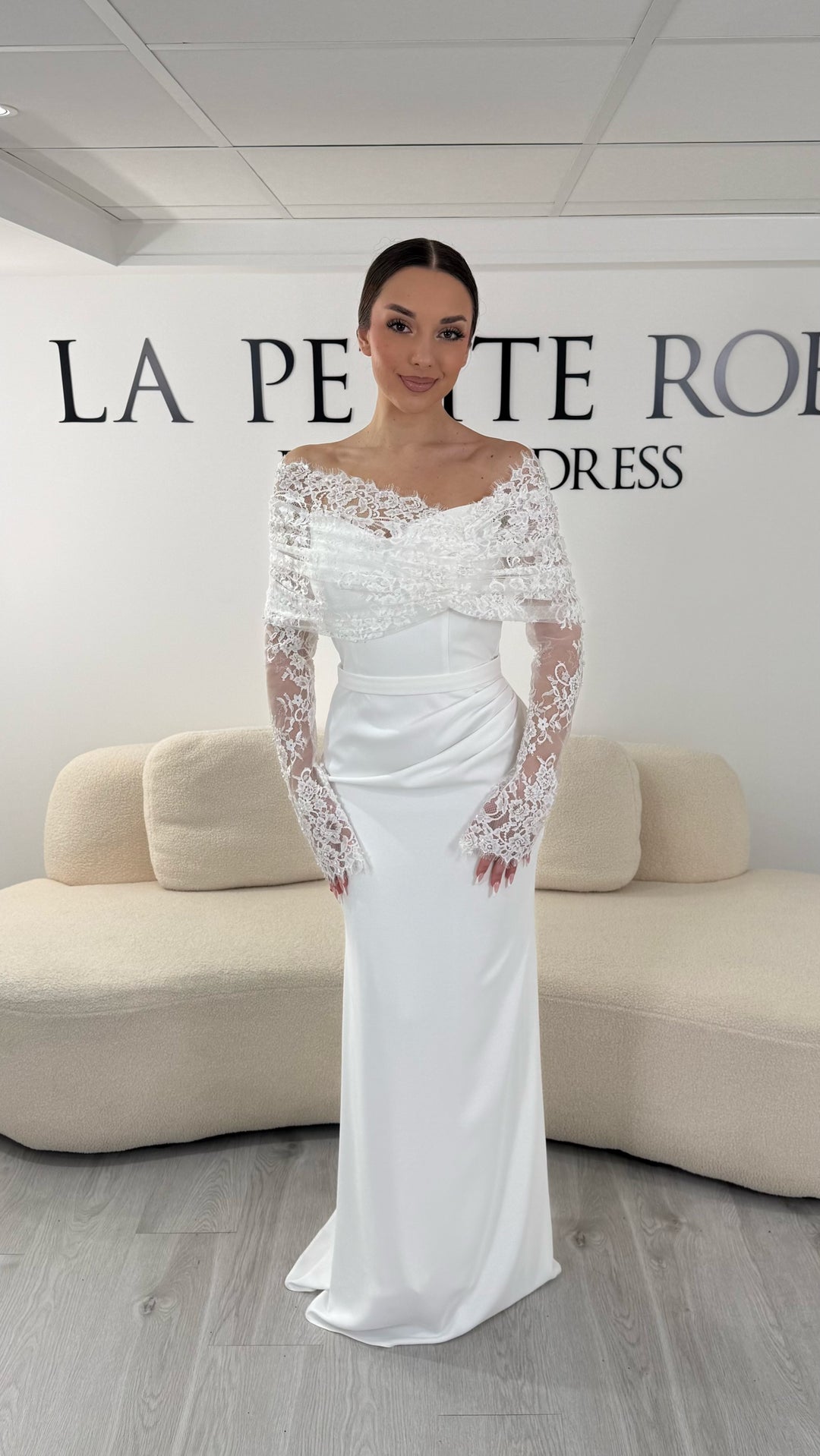 Robe de mariée blanche élégante avec col bateau en dentelle et manches longues. Robe longue sans fente idéale pour mariage chic.