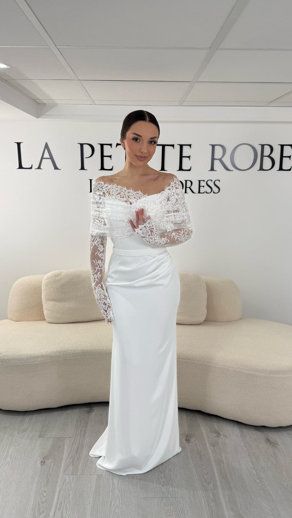 Robe de mariée blanche élégante avec col bateau en dentelle et manches longues. Robe longue sans fente idéale pour mariage chic.