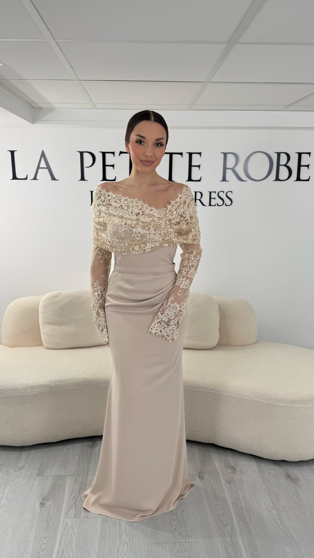 Robe de soirée beige élégante avec col bateau en dentelle et manches longues. Robe longue sans fente idéale pour soirée chic.