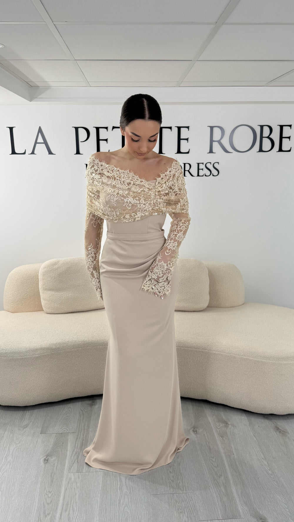 Robe de soirée beige élégante avec col bateau en dentelle et manches longues. Robe longue sans fente idéale pour soirée chic.