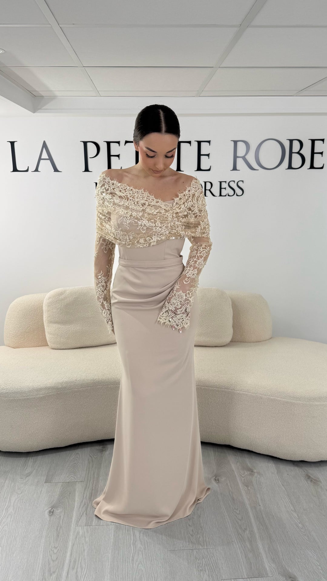 Robe de soirée beige élégante avec col bateau en dentelle et manches longues. Robe longue sans fente idéale pour soirée chic.