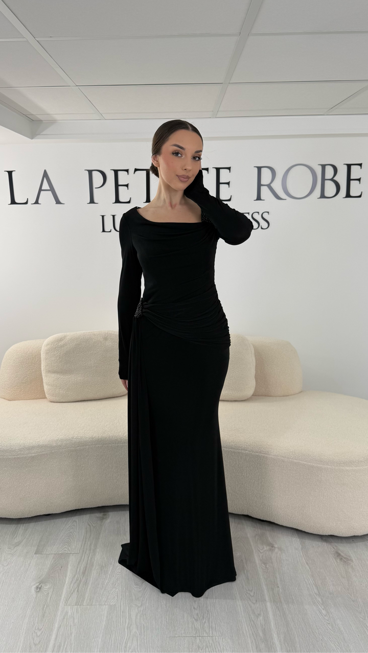 Robe de soirée noire élégante avec col bateau drapé et manches longues. Robe longue sans fente idéale pour soirée chic.