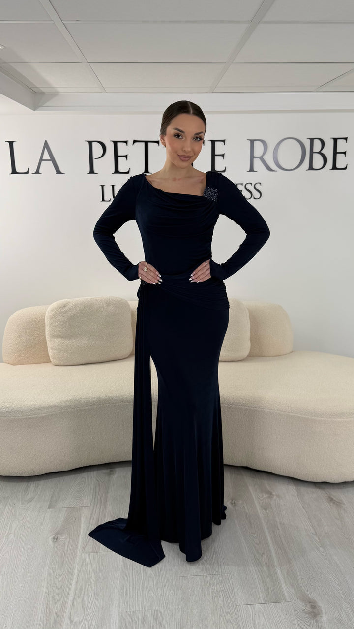 Robe de soirée bleu marine élégante avec col bateau drapé et manches longues. Robe longue sans fente idéale pour soirée chic.