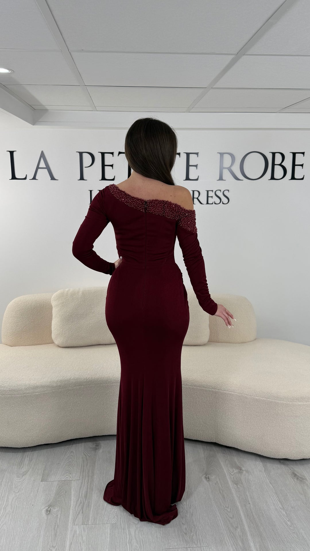 Robe de soirée bordeaux longue en jersey stretch, sans fente, avec col asymétrique et manches longues. Idéale pour vos soirées élégantes.