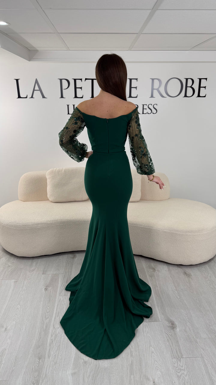 Robe de soirée vert émeraude longue, sans fente, avec col bateau et manches longues transparentes. Élégante pour vos événements.