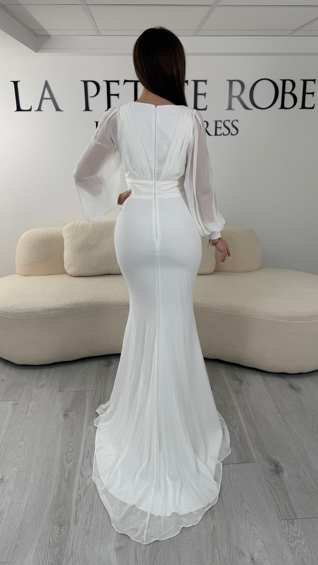 Robe de mariée blanche longue, sans fente, avec col cache-cœur et manches longues fluides. Élégante pour votre mariage.
