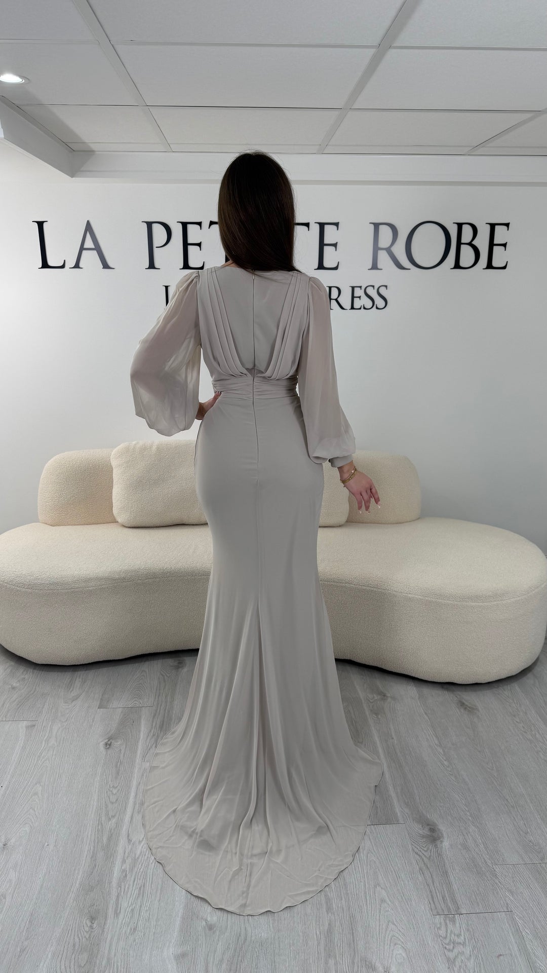 Robe de soirée nude longue avec fente, col cache-cœur et manches longues fluides. Élégante pour vos soirées et cérémonies.