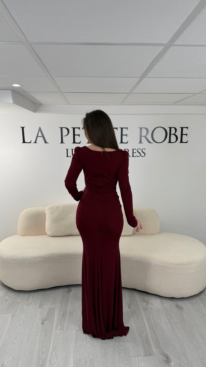 Robe de soirée bordeaux longue avec fente, col droit et manches longues. Élégante avec détails perlés pour vos soirées chic.