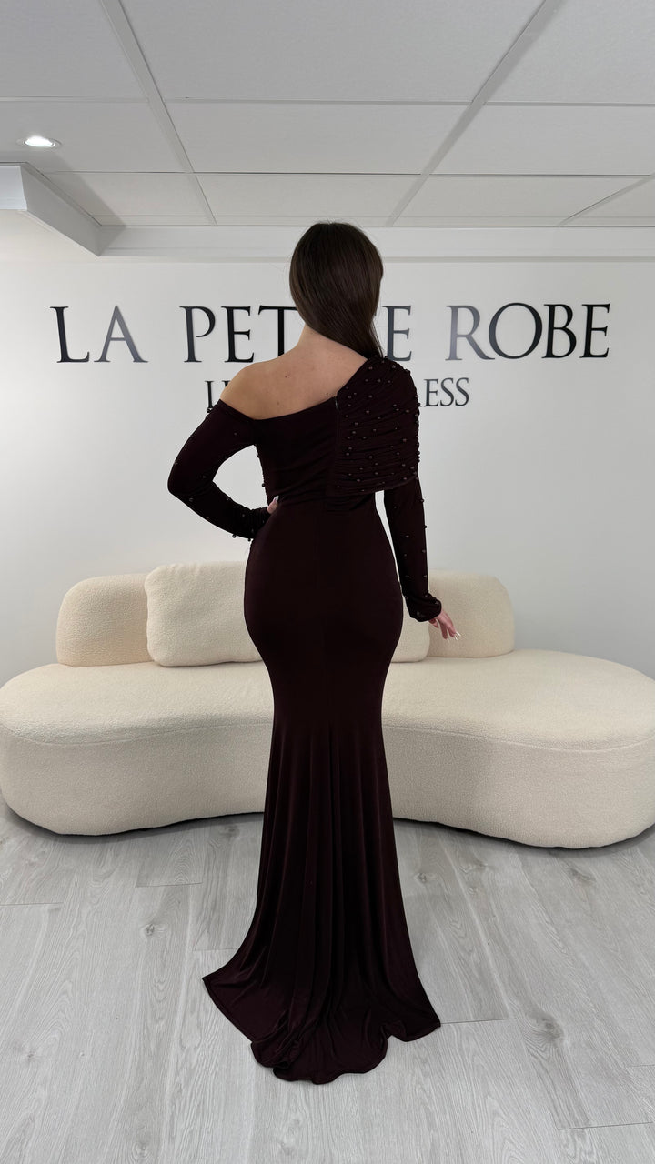 Robe de soirée marron longue, sans fente, avec col asymétrique et manches longues. Élégante avec détails perlés pour vos soirées.