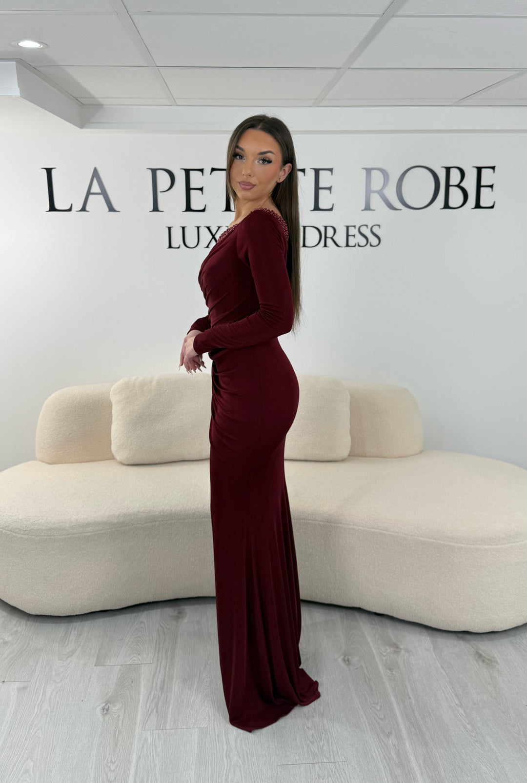 Robe de soirée bordeaux longue en jersey stretch, sans fente, avec col asymétrique et manches longues. Idéale pour vos soirées élégantes.