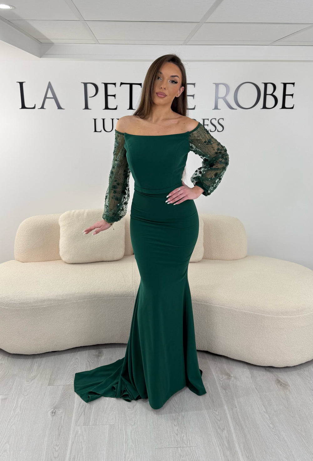 Robe de soirée vert émeraude longue, sans fente, avec col bateau et manches longues transparentes. Élégante pour vos événements.