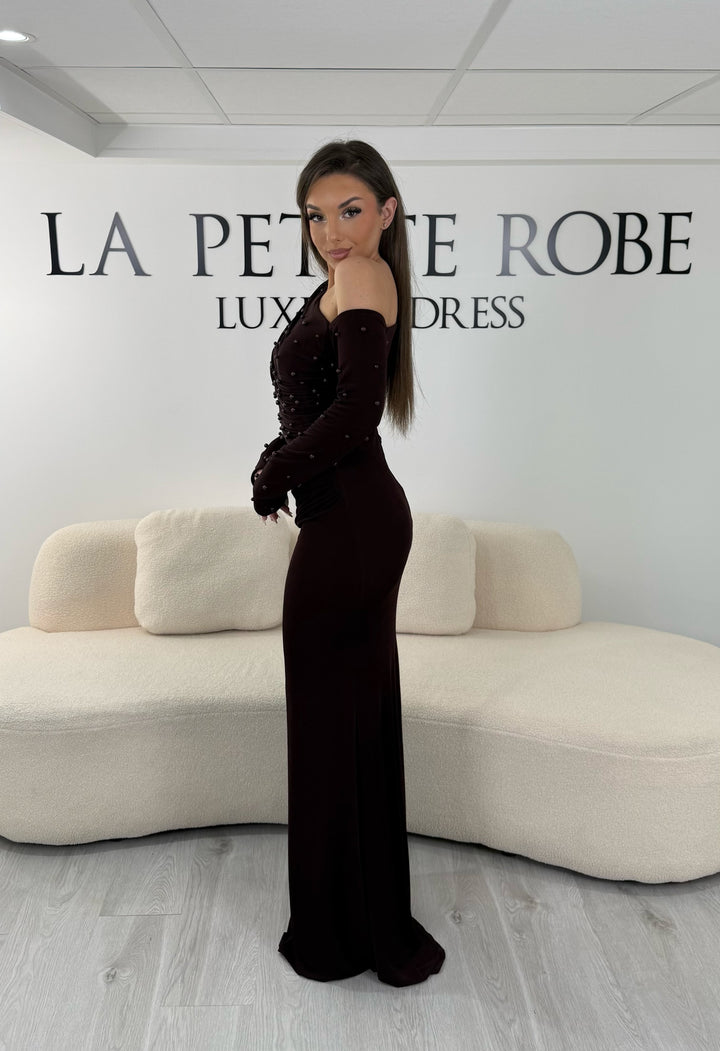 Robe de soirée marron longue, sans fente, avec col asymétrique et manches longues. Élégante avec détails perlés pour vos soirées.