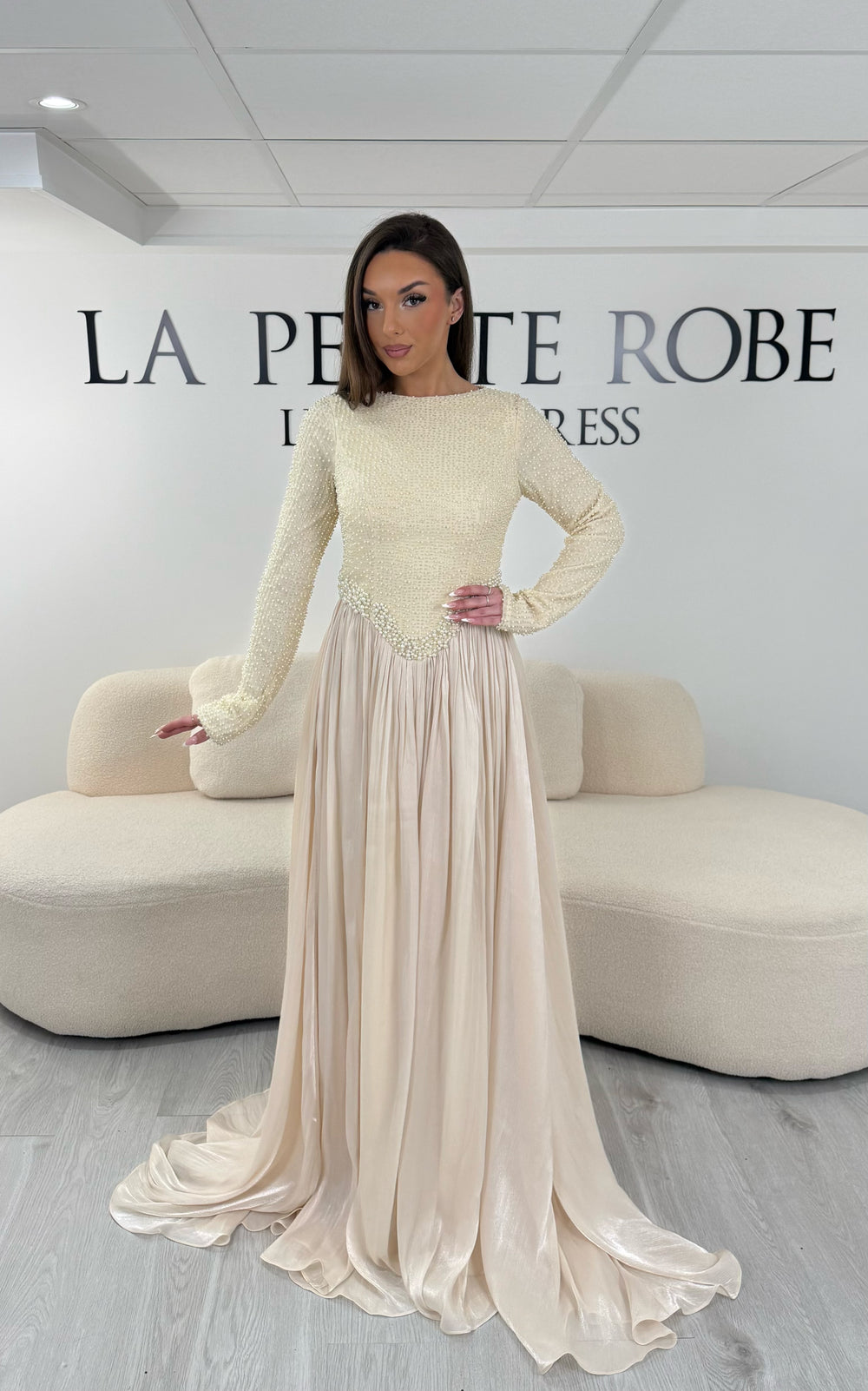 Robe de soirée beige longue, sans fente, avec col rond et manches longues. Élégante avec détails scintillants pour vos soirées.
