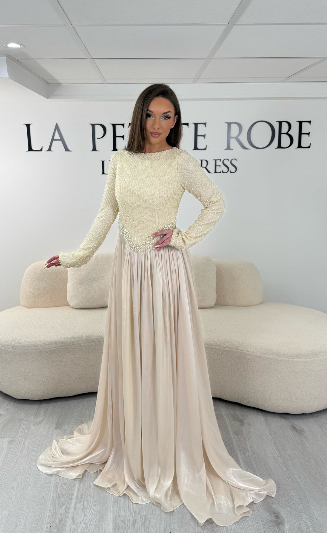 Robe de soirée beige longue, sans fente, avec col rond et manches longues. Élégante avec détails scintillants pour vos soirées.