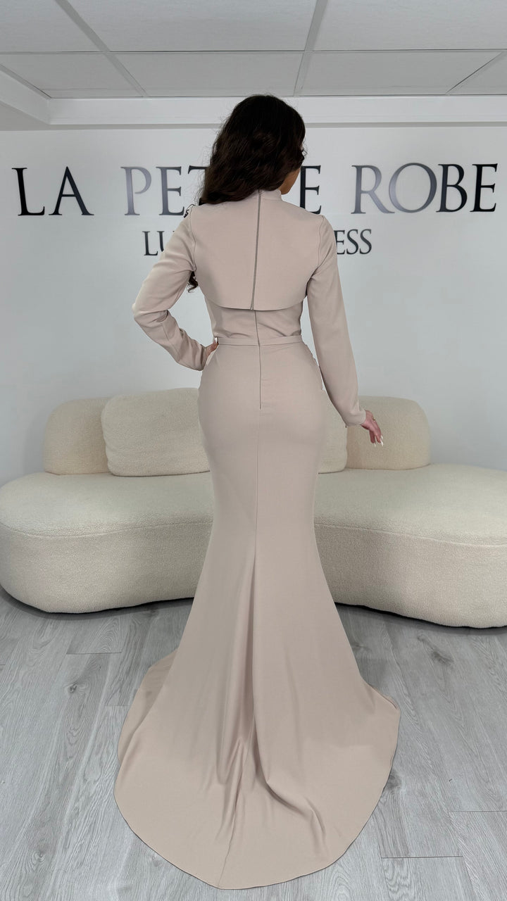Robe de soirée beige longue avec boléro amovible, manches longues et col montant. Élégante, sans fente, parfaite pour cérémonie et soirée chic.