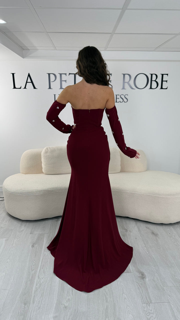 Robe de soirée bordeaux longue avec fente, bustier et manches amovibles. Élégante et tendance 2026, parfaite pour mariage ou soirée chic.
