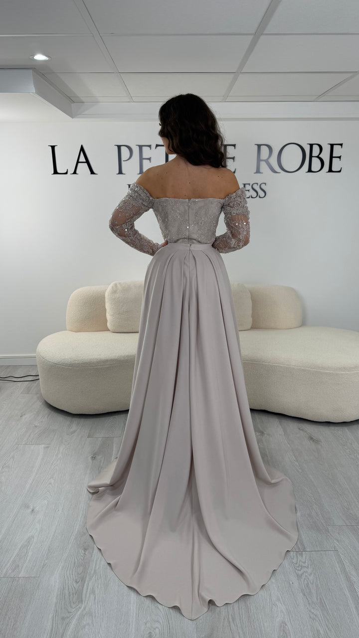 Robe de soirée beige longue avec dentelle, décolleté épaules dénudées et traîne amovible. Élégante, sans fente, idéale mariage 2026.