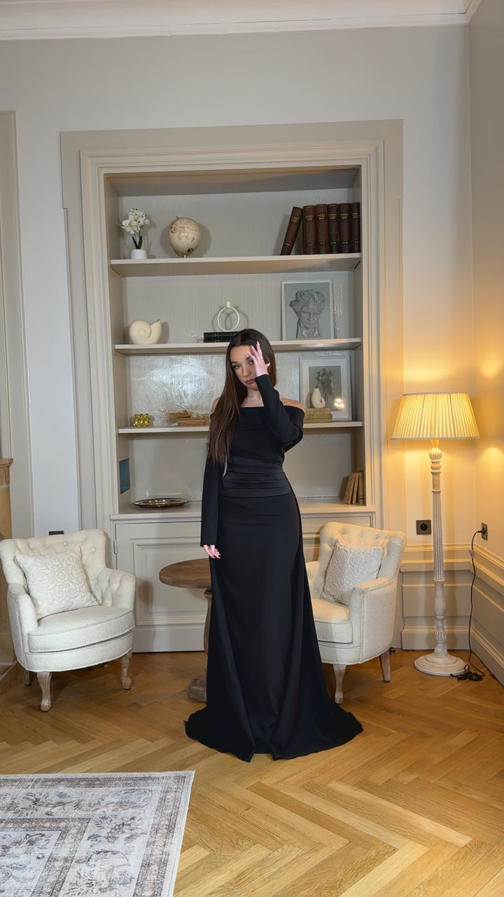 Robe de soirée élégante noire, coupe longue et fluide, col bateau chic et manches longues. Idéale pour mariage, gala et événements raffinés.