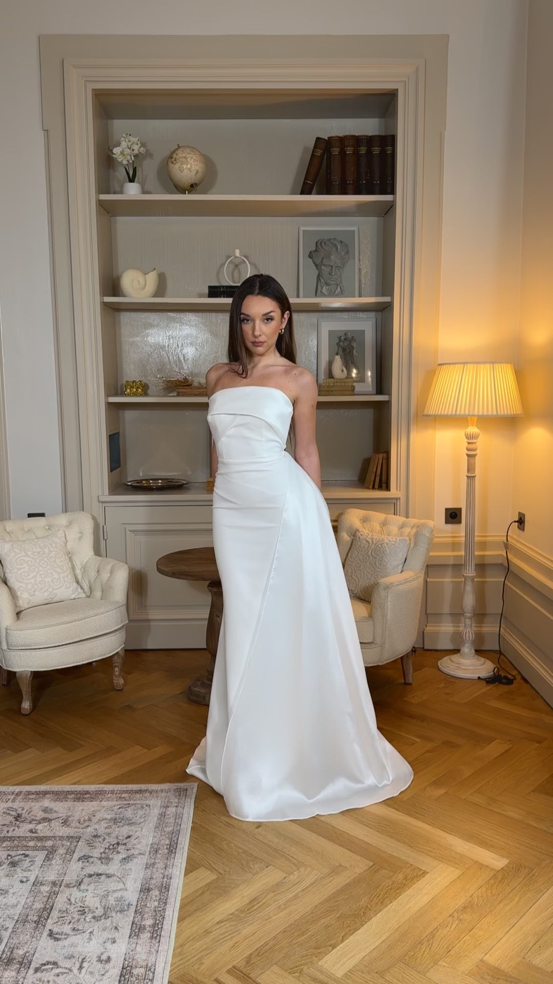 Longue robe de mariée blanche élégante, col bustier sans manches, coupe fluide sans fente. Une robe raffinée pour un mariage chic et intemporel.